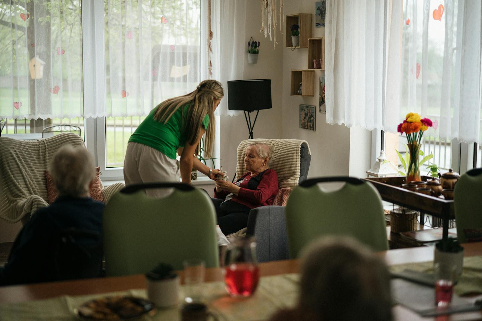 A caregiver assisting residents in a bright nursing home activity room
